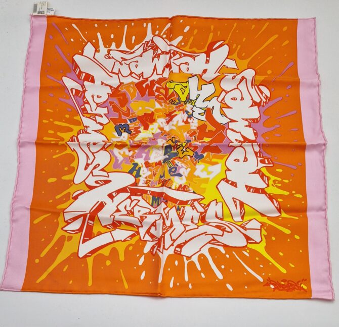 Cette pochette en soie ou gavroche Hermès GRAFF  a été dessinée par Kongo et publiée en 2012 Mesures 42 cm x 42 cm Ellel est à l état neuf avec ses étiquettes et provient des ventes privées . Couleurs orange , rose, blanc