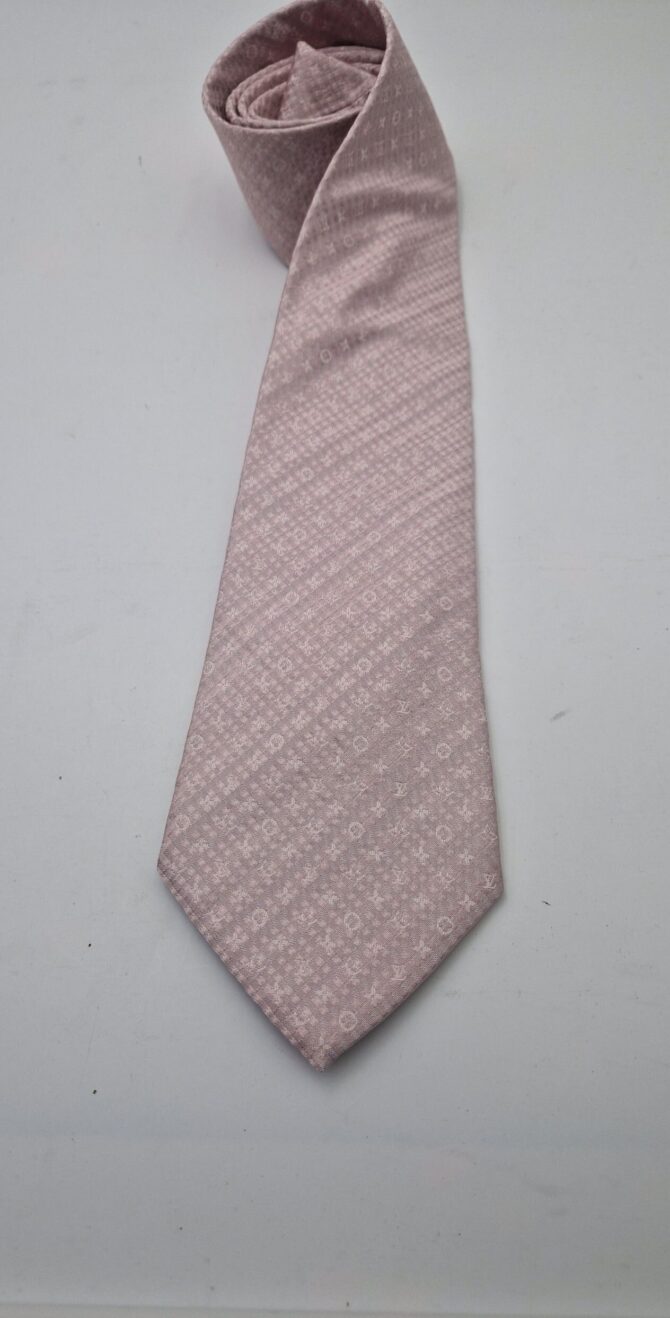 Cette belle cravate  Louis Vuitton rose pâle est ornée des motifs emblématiques de la marque.