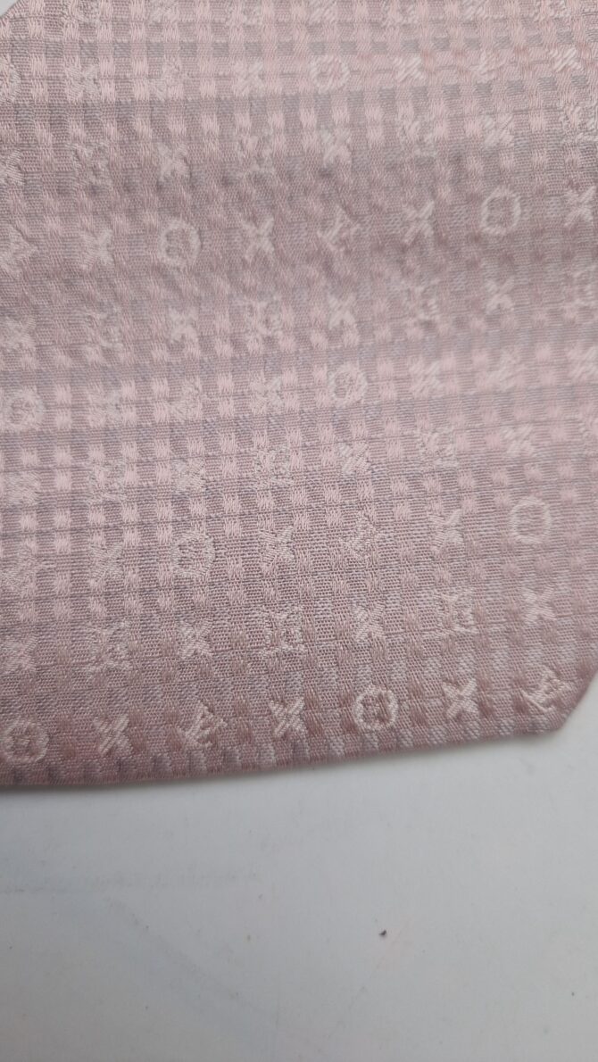 Cette belle cravate  Louis Vuitton rose pâle est ornée des motifs emblématiques de la marque.