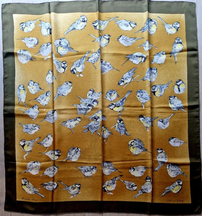 Carré Hermès en soie intitulé "Les Mésanges" de Xavier de Poret, édition de 1960, représentant des mésanges dessinées avec réalisme sur fond doré texturé, bordé de vert kaki.