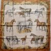 Carré Hermès en soie intitulé "Les Poulains" de Xavier de Poret, première édition 1960, illustrant des juments et poulains dans des scènes pastorales sur fond crème, encadré de bottes de foin dorées.