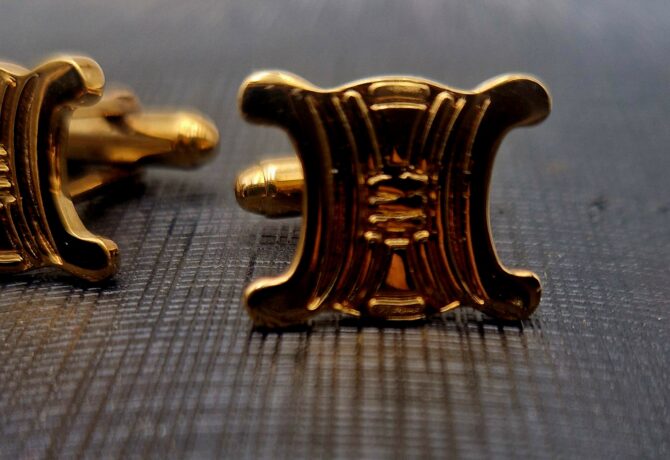 Boutons de manchette Céline dorés, motif Triomphe en relief.