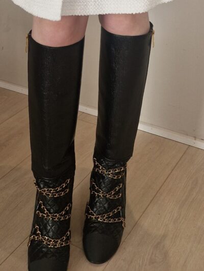 Bottes Chanel en cuir noir matelassé avec chaînes dorées et logo CC – Chanel black quilted leather boots with gold chains and CC charm.