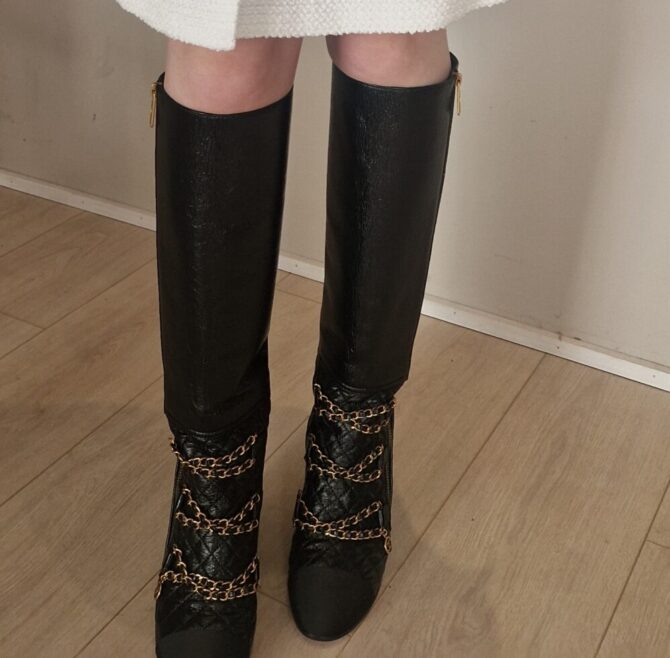 Bottes Chanel en cuir noir matelassé avec chaînes dorées et logo CC – Chanel black quilted leather boots with gold chains and CC charm.