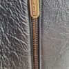 Détail de la fermeture éclair dorée gravée Chanel – Close-up of Chanel engraved gold zipper.