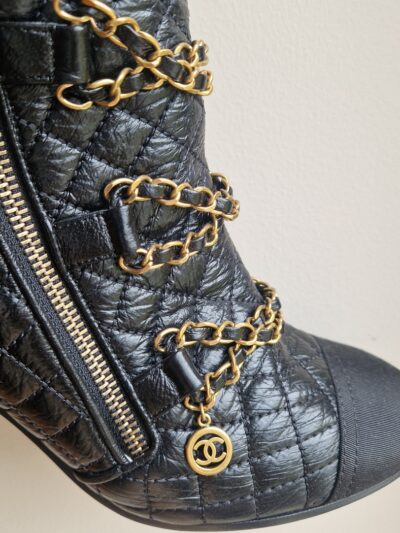Détail des chaînes dorées avec logo CC – Gold chains detail with CC logo charm.