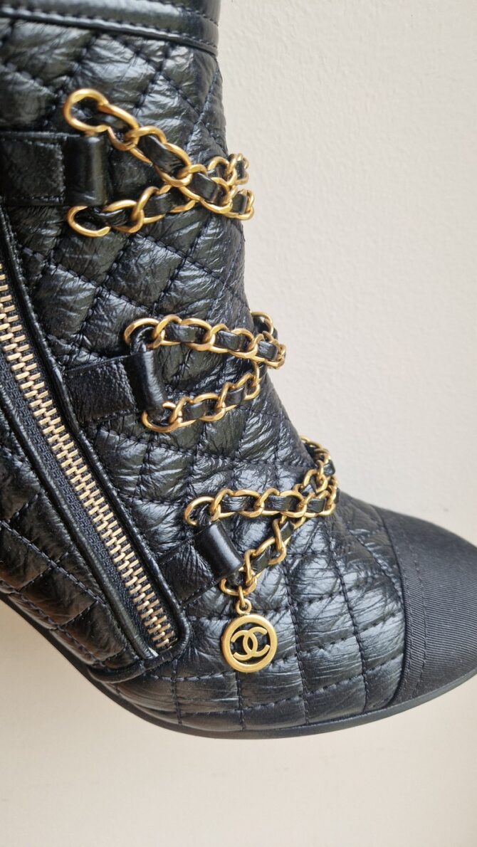 Détail des chaînes dorées avec logo CC – Gold chains detail with CC logo charm.