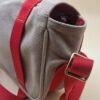 Profil du sac Louis Vuitton Antigua Besace PM, toile beige et sangles rouges EN : Side view of Louis Vuitton Antigua Besace PM, beige canvas with red straps
