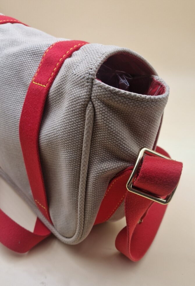 Profil du sac Louis Vuitton Antigua Besace PM, toile beige et sangles rouges EN : Side view of Louis Vuitton Antigua Besace PM, beige canvas with red straps