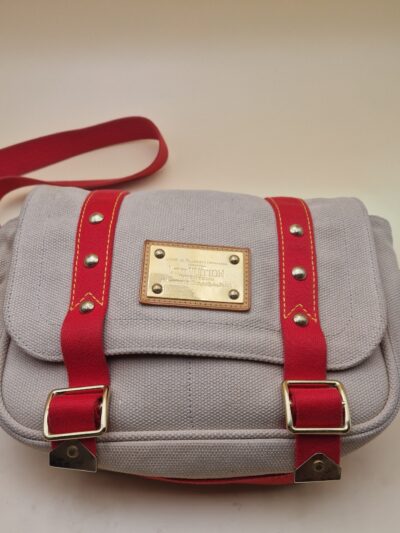 Sac Louis Vuitton Antigua Besace PM en toile beige avec sangles rouges et plaque Inventeur dorée EN : Louis Vuitton Antigua Besace PM in beige canvas with red straps and gold Inventeur plaque