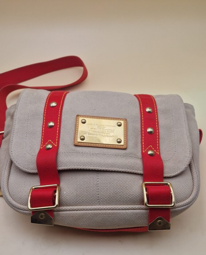 Sac Louis Vuitton Antigua Besace PM en toile beige avec sangles rouges et plaque Inventeur dorée EN : Louis Vuitton Antigua Besace PM in beige canvas with red straps and gold Inventeur plaque