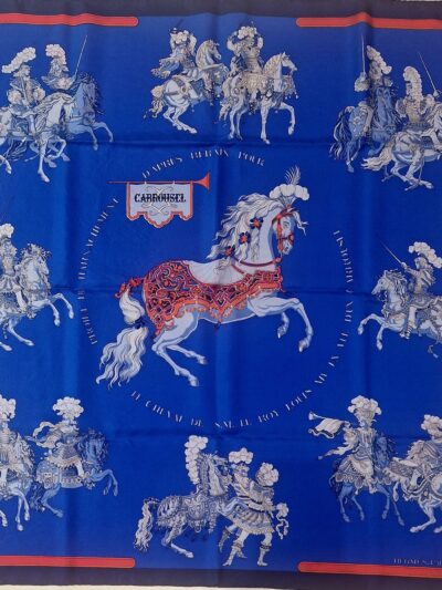 Carré Hermès Carrousel par Christiane Vauzelles, édition 1984, vue d’ensemble sur fond bleu roi. EN : Hermès scarf Carrousel by Christiane Vauzelles, 1984 issue, full view on royal blue background.