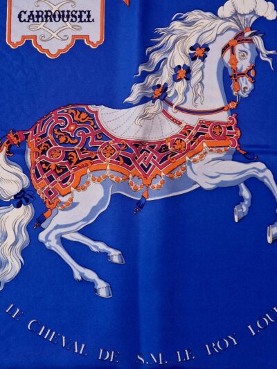 Gros plan du cheval central richement harnaché et des cavaliers du carré Carrousel. EN : Close-up of the richly harnessed central horse and riders on Carrousel scarf.