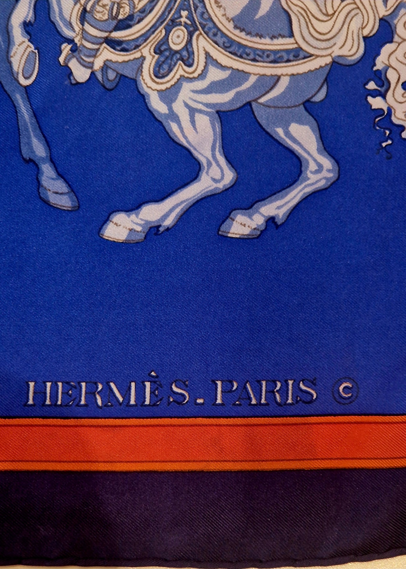 Signature Hermès Paris et roulotté main du carré Carrousel. EN : Hermès Paris signature and hand-rolled hem of Carrousel scarf.