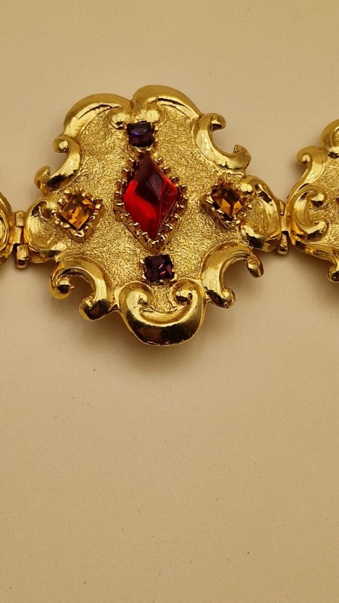 Bracelet Christian Lacroix doré baroque avec pierres rouges, bleues et ambrées, signé Made in France, dans sa boîte d’origine.