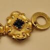 Bracelet Christian Lacroix doré baroque avec pierres rouges, bleues et ambrées, signé Made in France, dans sa boîte d’origine.