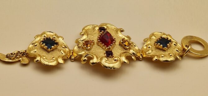 Bracelet Christian Lacroix doré baroque avec pierres rouges, bleues et ambrées, signé Made in France, dans sa boîte d’origine.