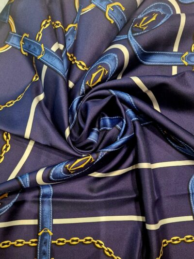 Carré Must de Cartier vintage 1990 en soie bleu marine à motif de sangles et chaînes dorées, état neuf.