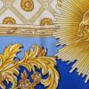 Foulard en soie bleu et or « La Grande Écurie du Roy – Versailles » signé Jacques Portier, représentant trois chevaux solaires entourés de motifs baroques et de visages rayonnants.